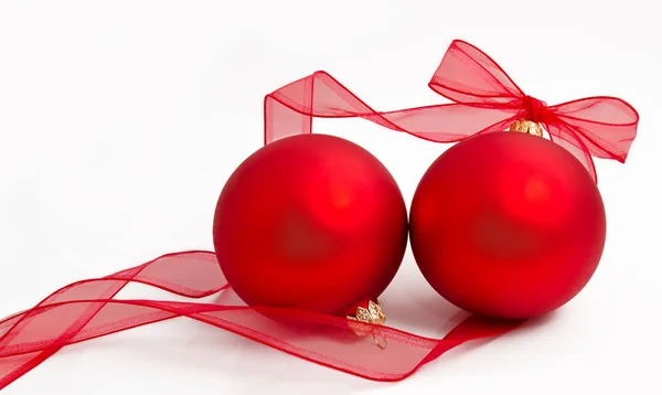 Due palline rosse di Natale con nastro su un bianco — Foto Stock