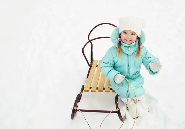 Bambina seduta sulla slitta in giorno d'inverno — Foto Stock