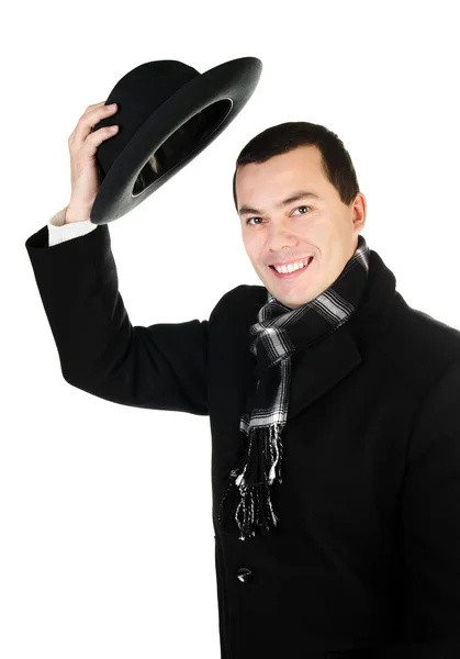 Jovem sorridente de casaco preto e cachecol segurando o chapéu isolado — Fotografia de Stock