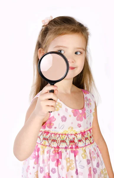 Beautiful little girl looking through a magnifying glass — Stock Photo, Image