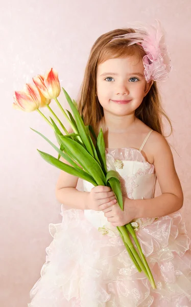 Smiling little girl with tulips — Stock Photo, Image