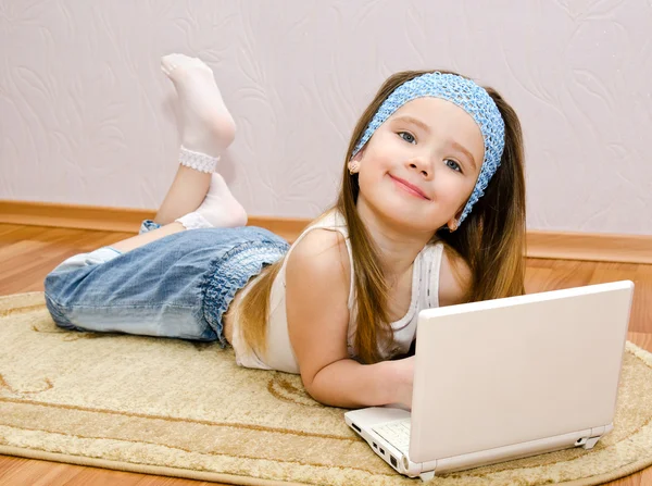 Lachende meisje met een laptop thuis op de verdieping — Stockfoto