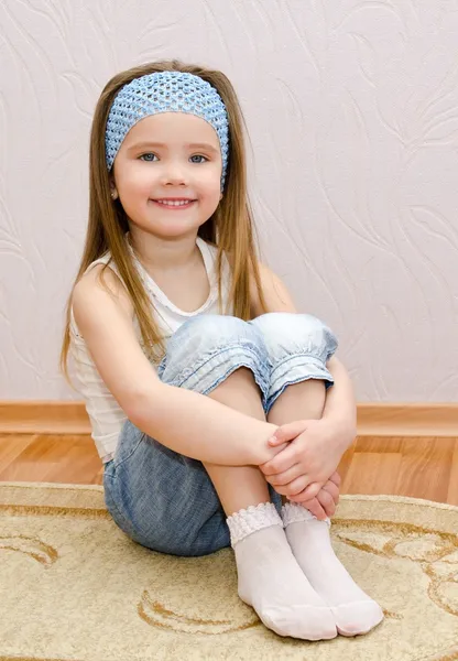 Smiling little girl sitting on a house floor — Stock Photo, Image