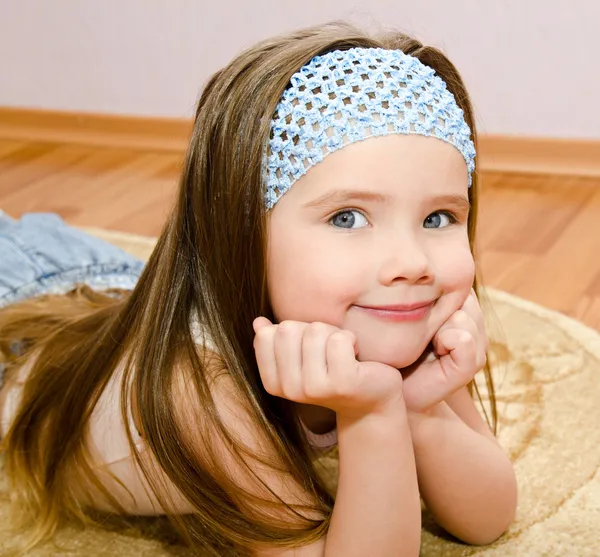 La bambina sorridente si trova su un piano di casa — Foto Stock