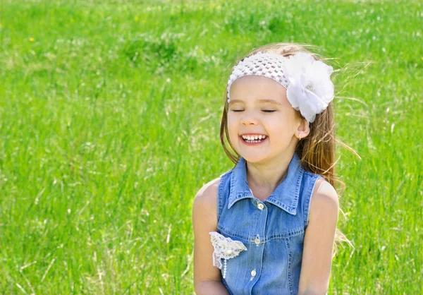 Skrattar söta lilla flickan på ängen — Stockfoto