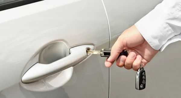 La mano del hombre insertando una llave en la cerradura de la puerta de un coche —  Fotos de Stock