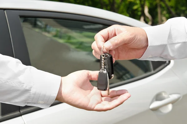 Homem entregando outra pessoa automóvel chaves carro novo — Fotografia de Stock