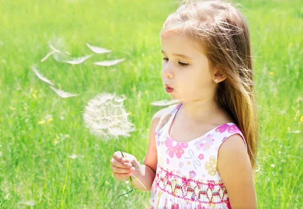 Hermosa niña soplando diente de león — Foto de Stock