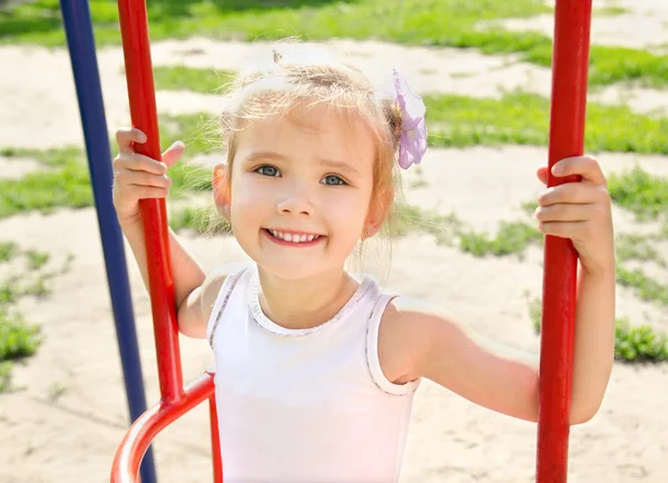 Smiling little girl on swing in playground — Stock Photo, Image
