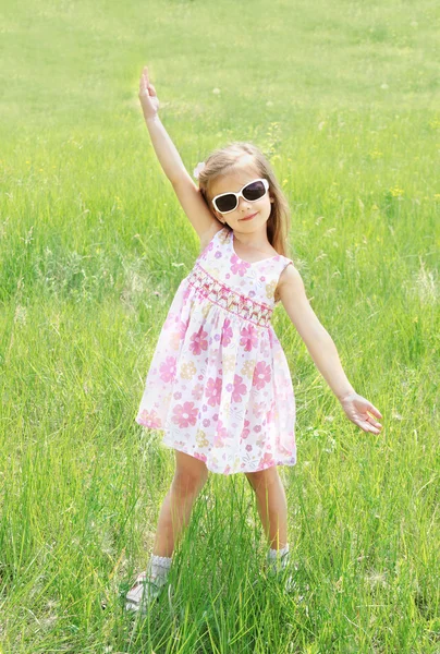 Menina sorridente bonito em óculos de sol no prado — Fotografia de Stock