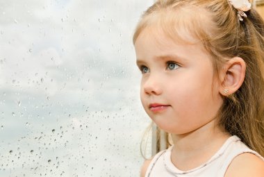 yağmurlu bir günde pencereden dışarı bakarak küçük kız