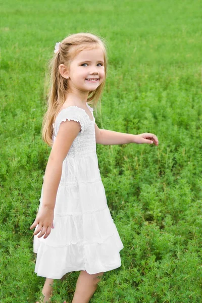 Gülümseyen küçük kız yeşil sahada yürüyor — Stok fotoğraf