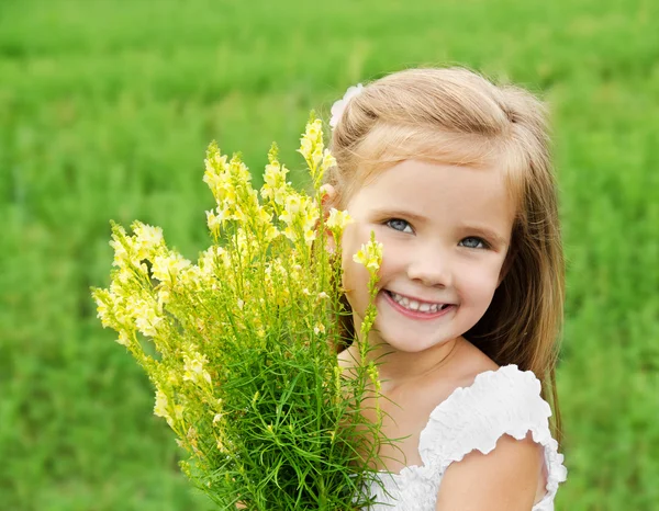 Sonriente niña linda con flores en el prado — Foto de Stock