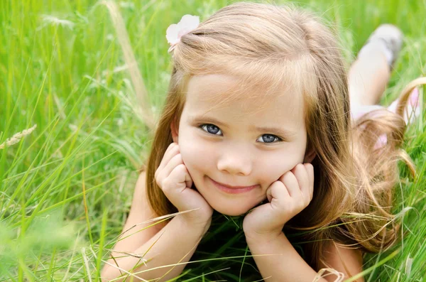 Schattig klein meisje liggen in gras — Stockfoto