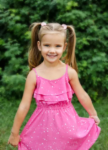 Outdoor portrait of smiling little girl holding flower — Stock Photo, Image