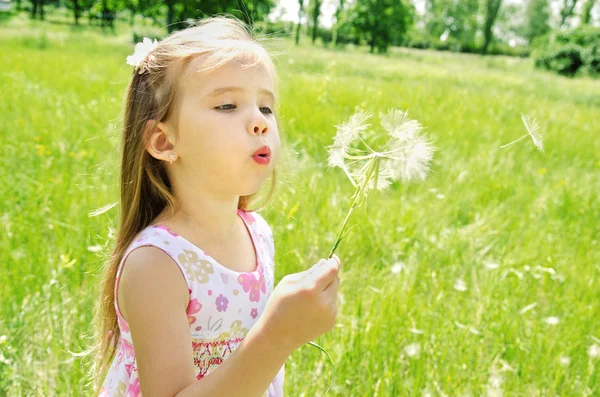 Hermosa niña soplando diente de león — Foto de Stock