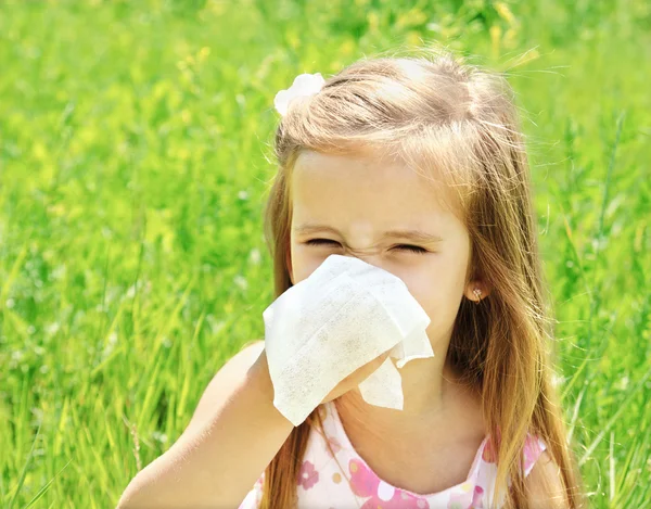 Menina está soprando o nariz no prado verde — Fotografia de Stock