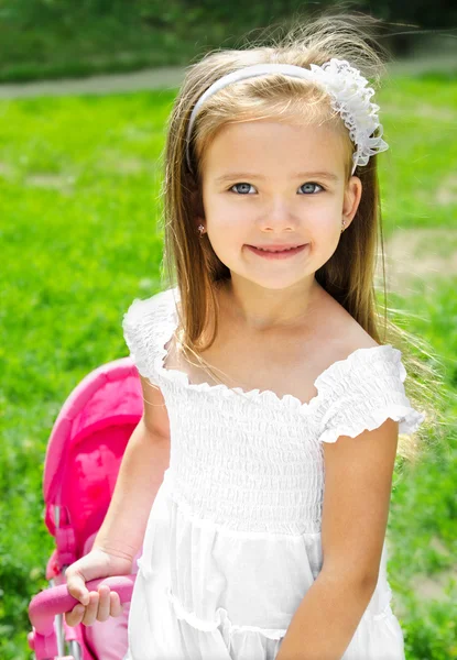 Süßes kleines Mädchen mit ihrem Spielzeugwagen und Puppe — Stockfoto