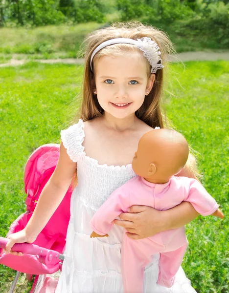 Cute little girl with her toy carriage and doll — Stock Photo, Image