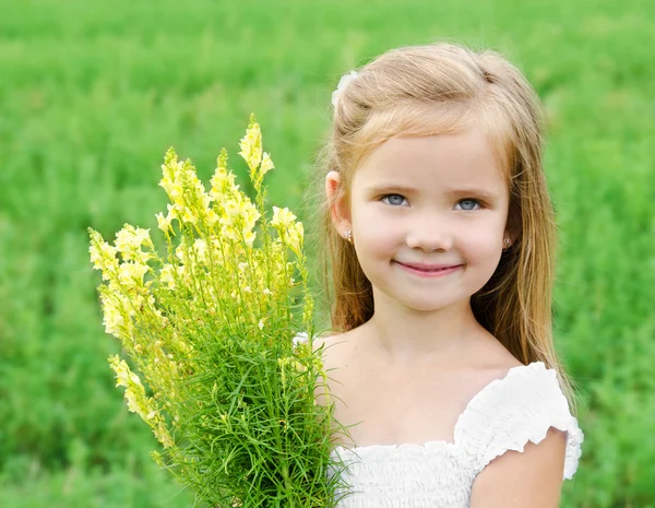 Ler söt liten flicka med blommor på ängen — Stockfoto