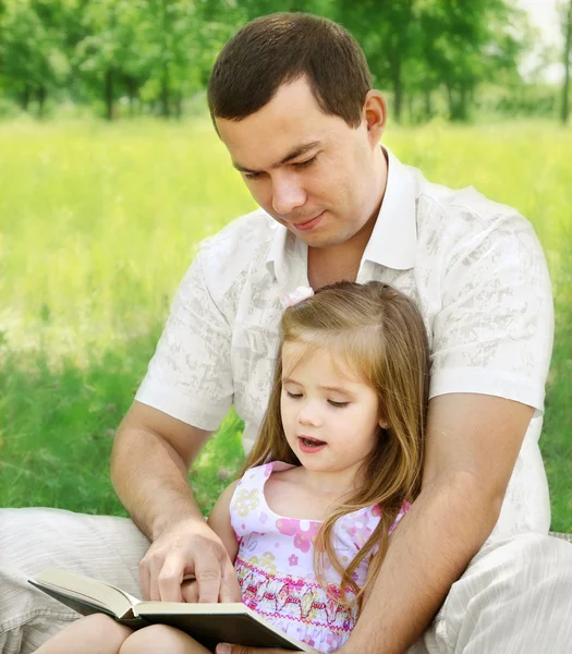 Padre con hija leyendo en el parque — Foto de Stock