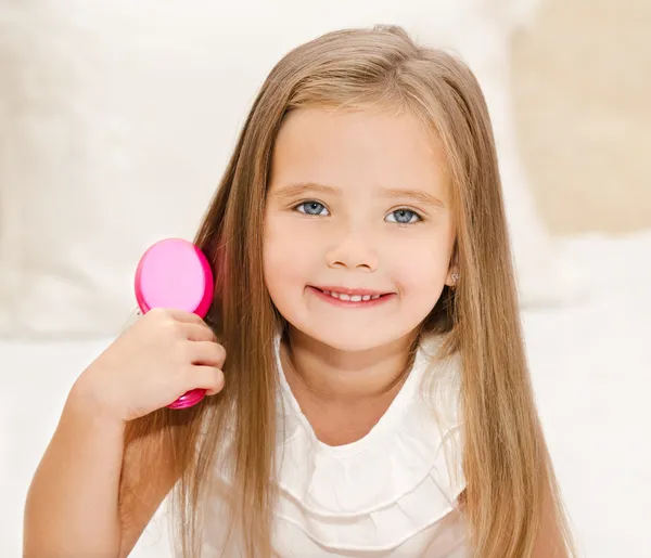 Retrato de uma menina sorridente escovando o cabelo — Fotografia de Stock