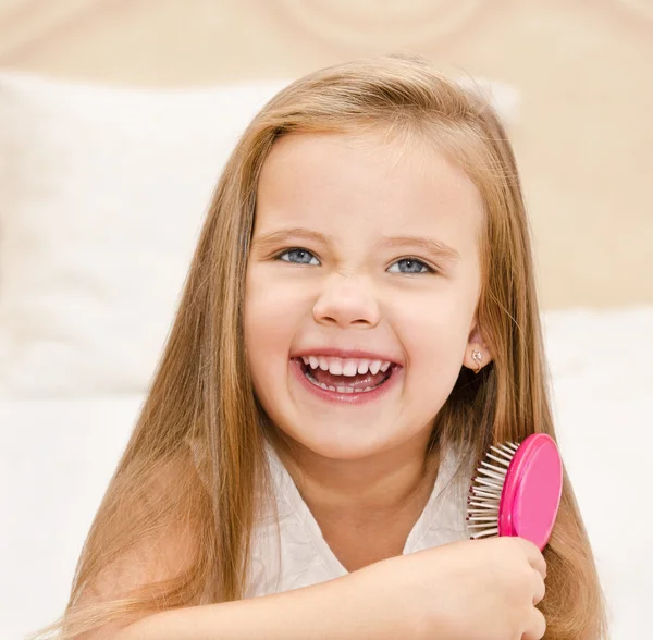 Retrato de uma menina sorridente escovando o cabelo — Fotografia de Stock