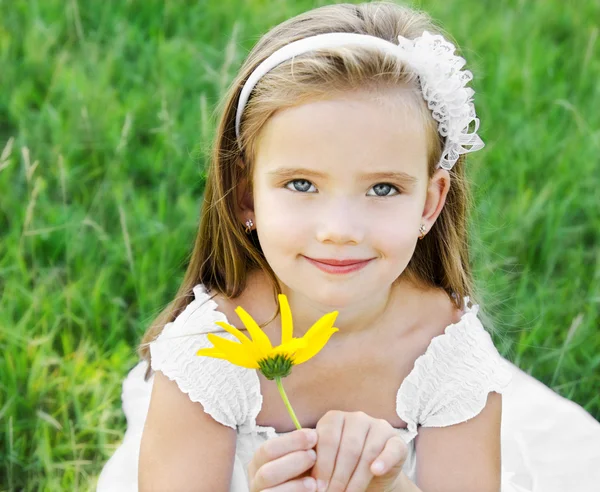 Schattig klein meisje op de weide met bloem — Stockfoto