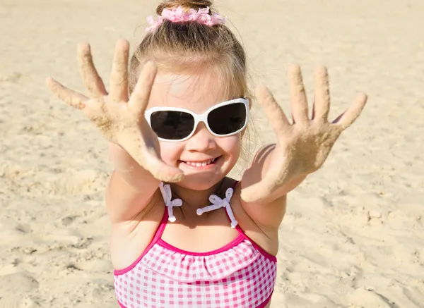 Smiling little girl playing on beach — Stock Photo, Image
