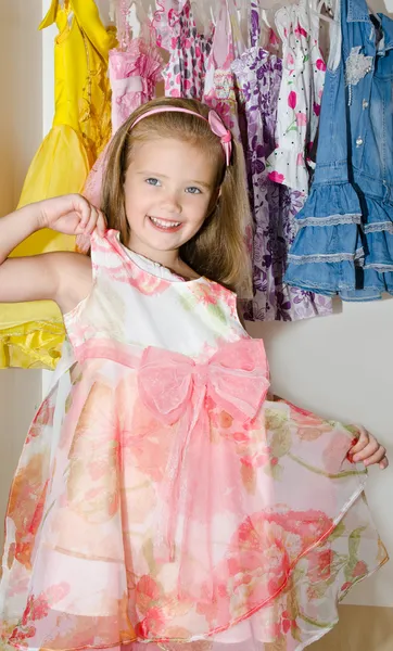 Bonito sorrindo menina escolhe um vestido do guarda-roupa — Fotografia de Stock