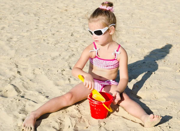 小さな女の子がビーチで遊んでの笑みを浮かべてください。 — ストック写真