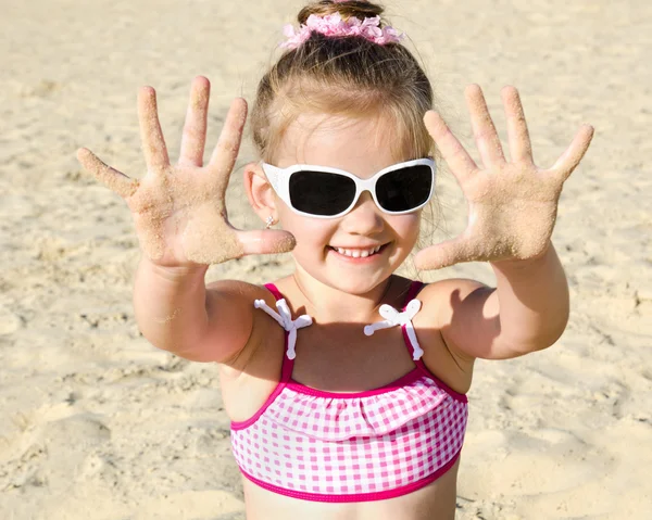 Smiling little girl playing on beach — Stock Photo, Image