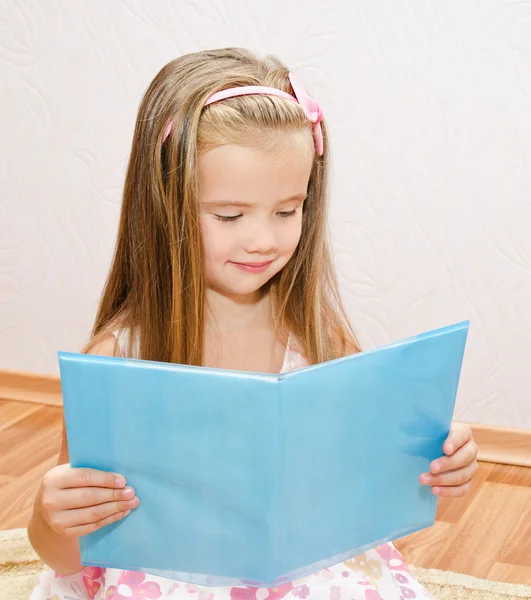 Sevimli küçük bir kız bir kitap okuma gülümseyerek — Stok fotoğraf