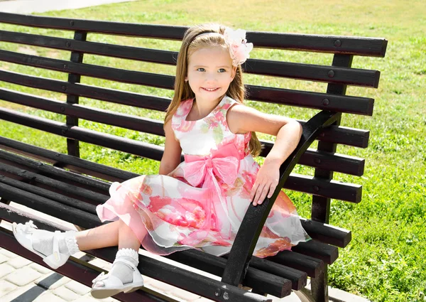 Outdoor portrait of little girl sitting on a bench — Stock Photo, Image