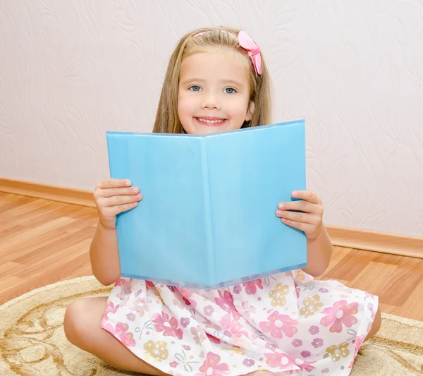 Sød smilende lille pige læser en bog - Stock-foto