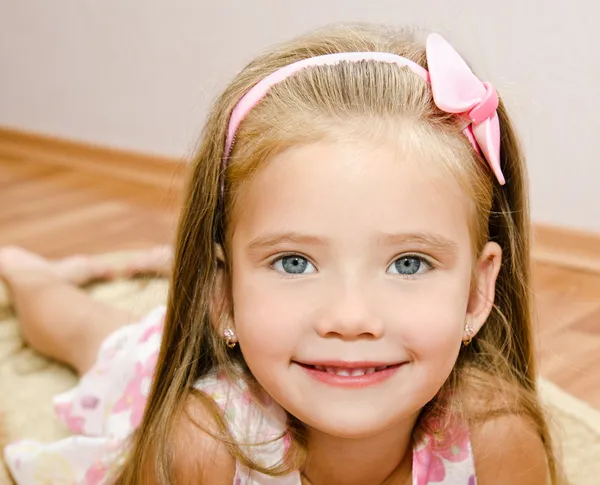 La bambina sorridente si trova su un piano di casa — Foto Stock