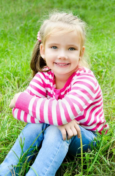 Linda niña sonriente tendida en la hierba en el prado — Foto de Stock