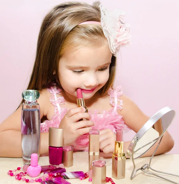 Kind cosmetica schattig klein meisje met lippenstift en spiegel — Stockfoto