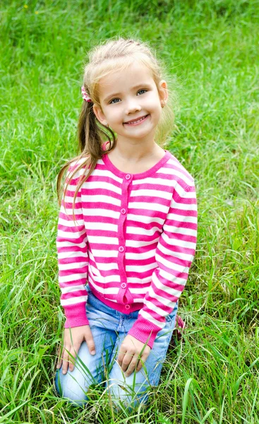 Schattig lachende klein meisje liggen in gras op de weide — Stockfoto