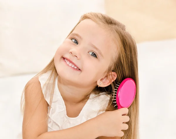 Retrato de uma menina sorridente escovando o cabelo — Fotografia de Stock