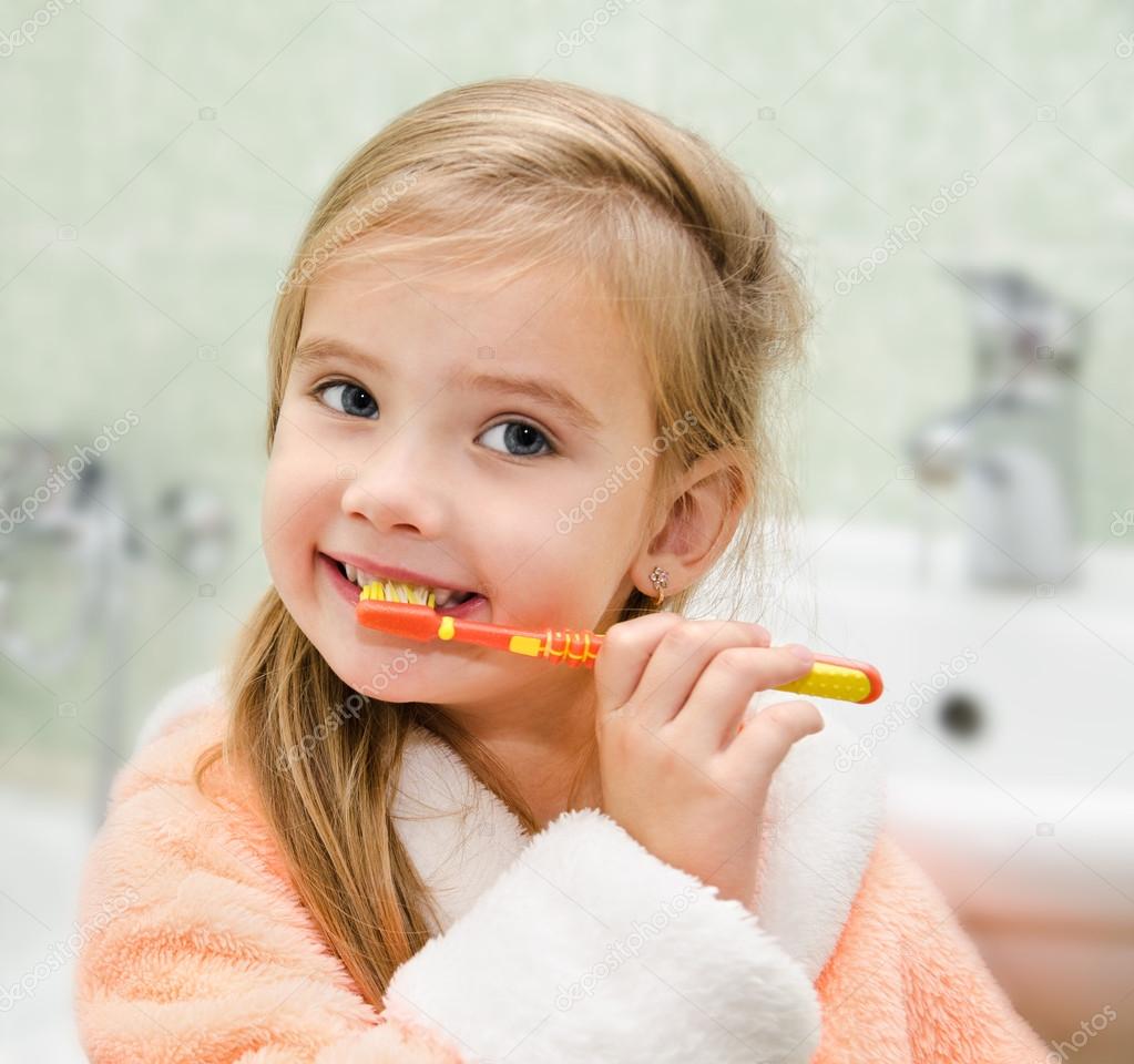 Smiling little girl brushing teeth
