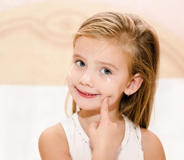 Cute little girl applying cream — Stock Photo, Image