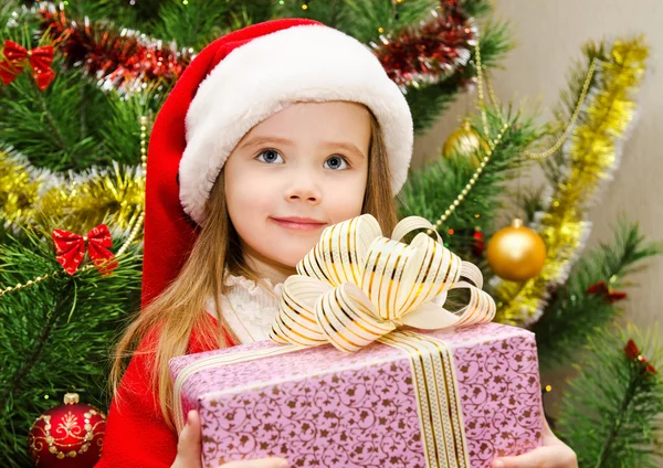 Klein meisje in kerstmuts met heden hebben een kerst — Stockfoto