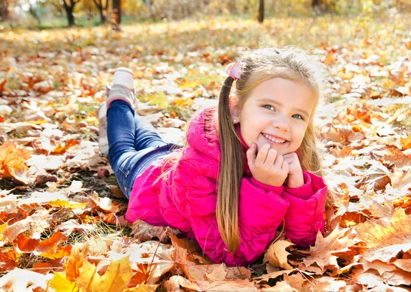 Осенний портрет милой маленькой девочки, лежащей в кленовых листьях — стоковое фото