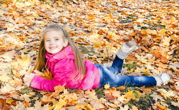 Retrato de outono de menina bonito deitado em folhas de bordo — Fotografia de Stock