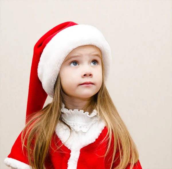 Niedliches kleines Mädchen mit Weihnachtsmütze träumt und schaut auf — Stockfoto