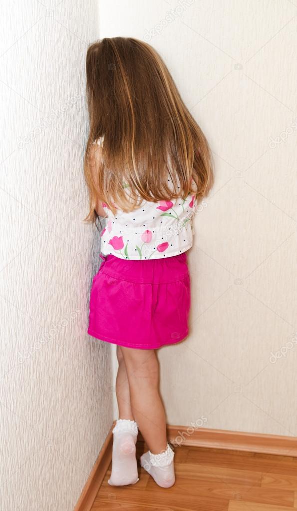 Naughty little girl is standing in the corner