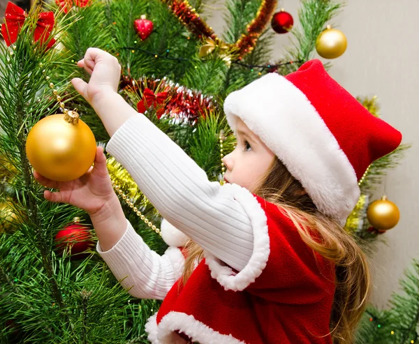 Kislány santa kalap díszítették a karácsonyfát — Stock Fotó