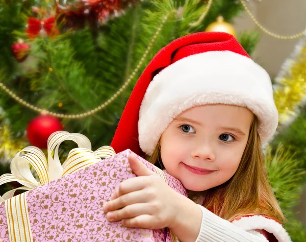 Carino bambina in cappello di Babbo Natale con regalo — Foto Stock