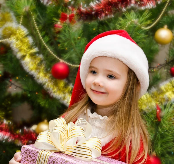 Cute little girl in santa hat with present Stock Photo